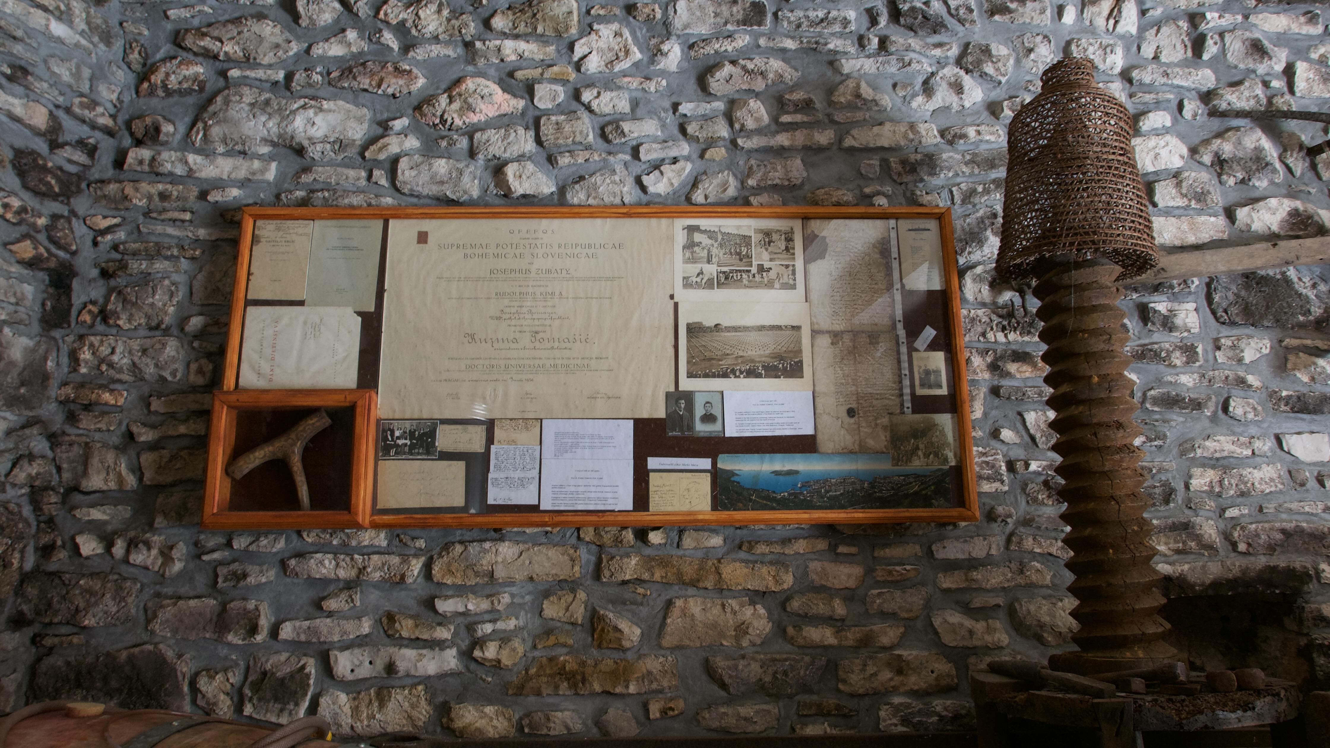 Left wall of the cellar — glazed walnut display case with four original documents behind glass