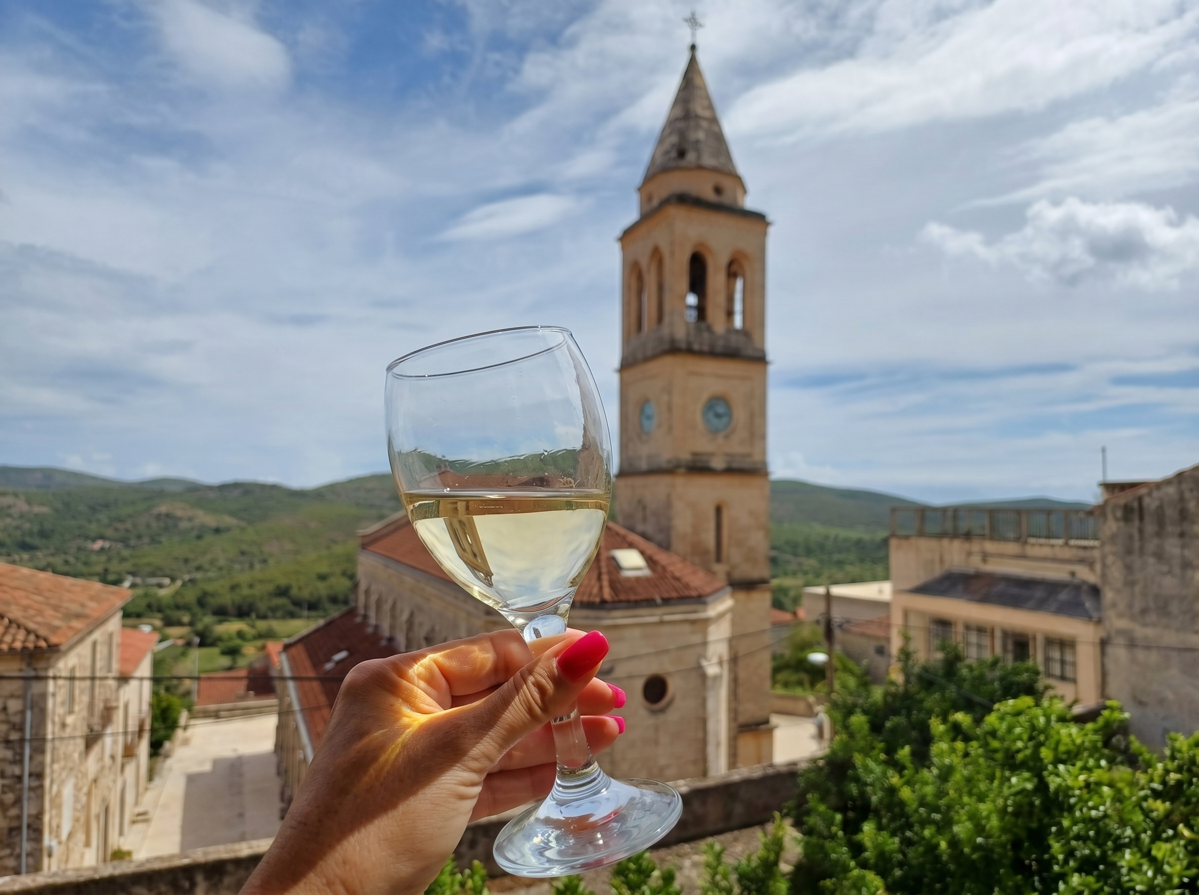 A glass of Pošip raised against the five-hundred-year bell-tower of Smokvica