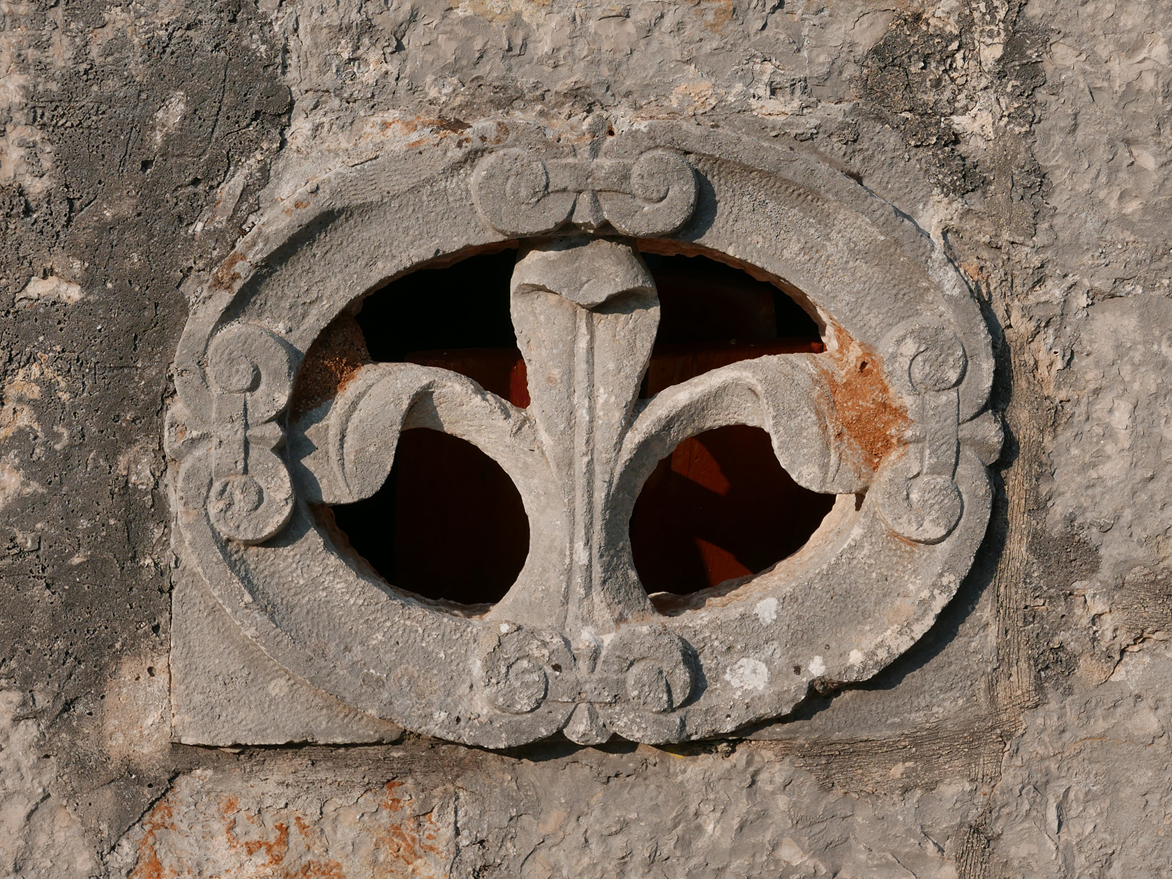Ancient carved stone relief in the chapel wall showing the same flower motif