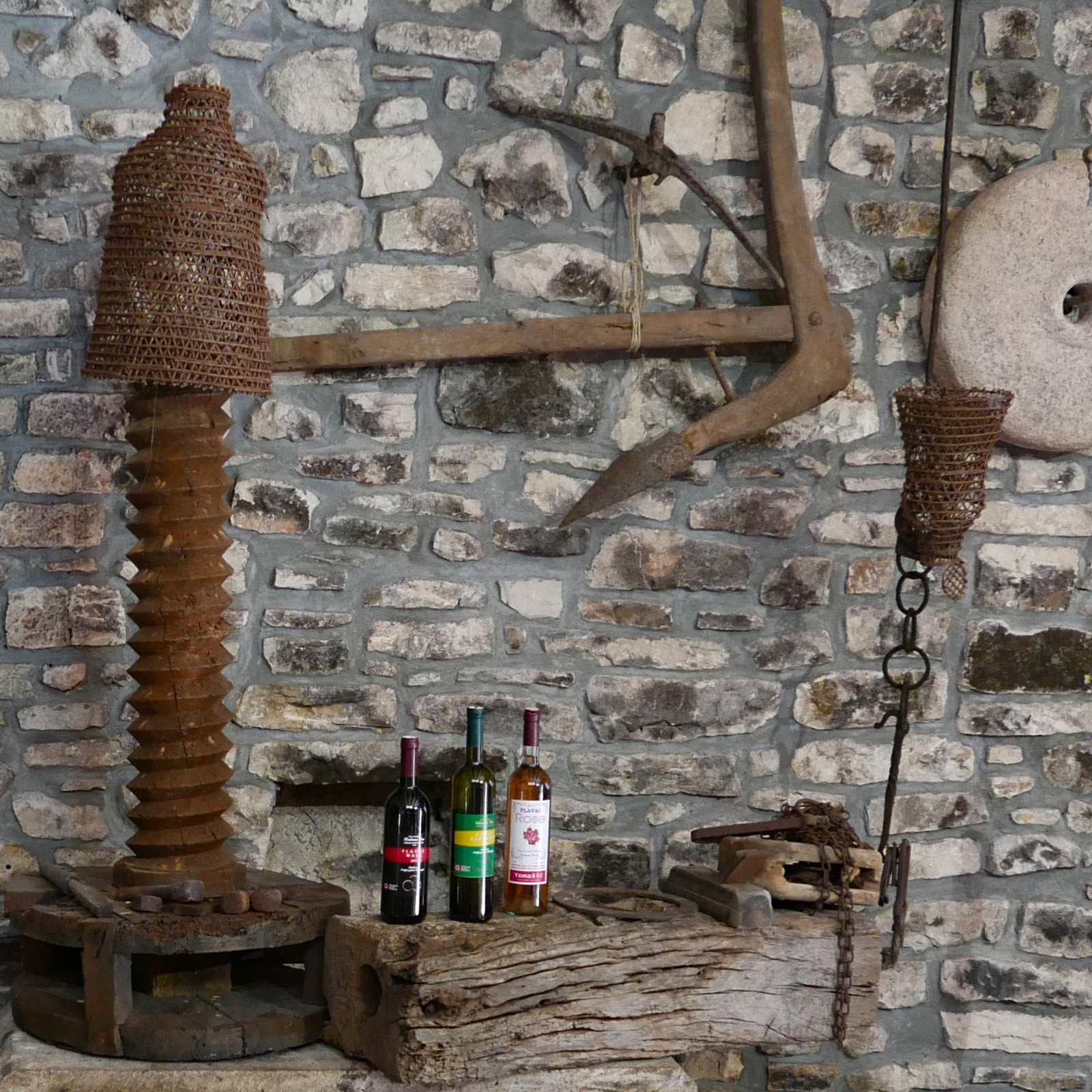 The wicker-wrapped wine press in the cellar — a wooden cone bound in cane with a single great wooden screw